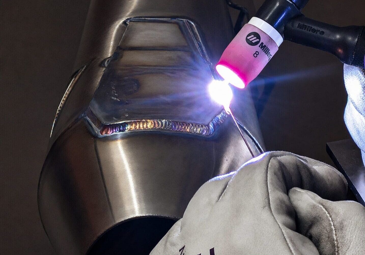 Gloved hand TIG welding stainless steel pipe seam